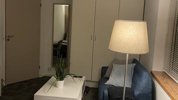 Une chambre d’hôtel comprenant un lit, un bureau avec une plante, une chaise, une lampe, une armoire et un miroir.