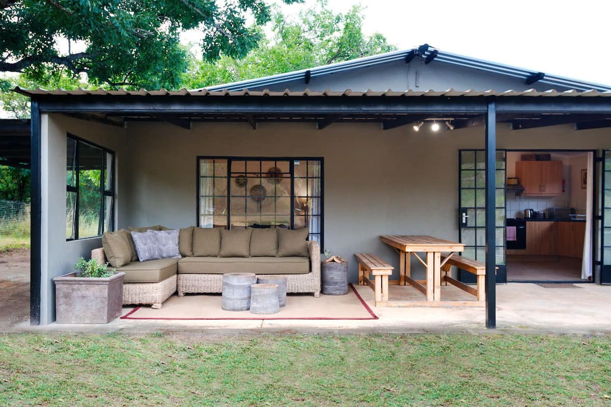 A covered outdoor seating area with a sofa, a table, and a bench.
