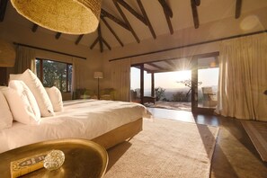 A spacious bedroom with a large bed, a view of the outdoors, and a rustic ceiling. - Tomjachu Bush Retreat (Mbombela)