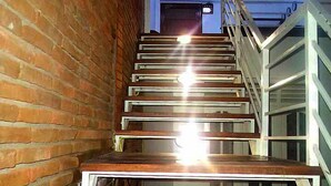 A staircase with metal railings and wooden steps, leading to a door with a light fixture above it. - City Resort (Anuradhapura)