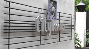 A metal sign with the text "City Resort" mounted on a wall with horizontal bars.