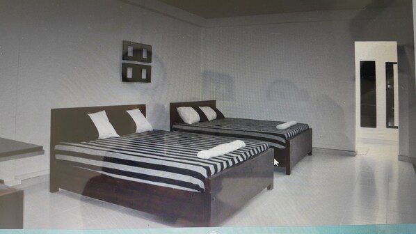 A bedroom with two beds, a window, and a door.