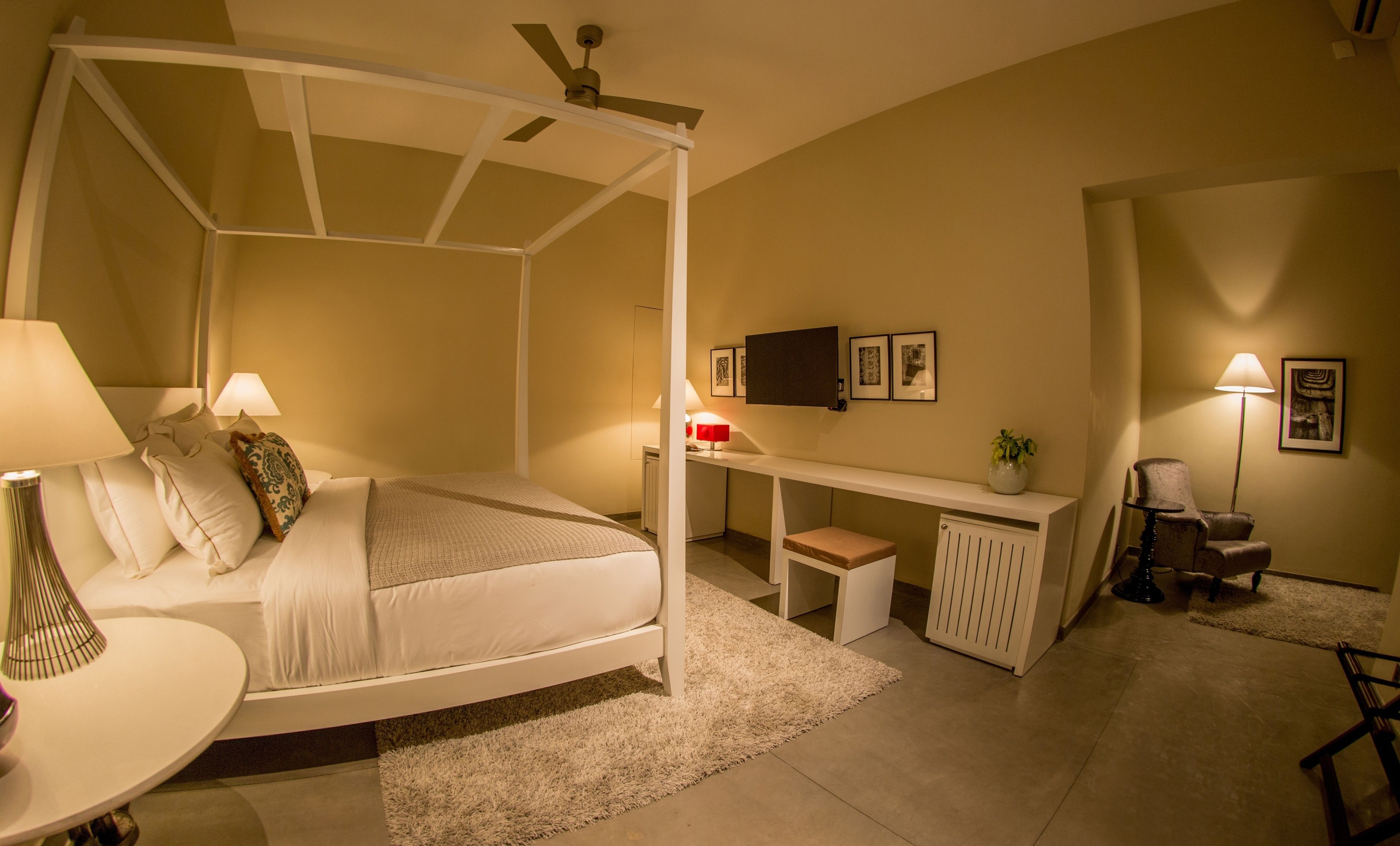 A bedroom with a four-poster bed, a desk, a chair, and a radiator.