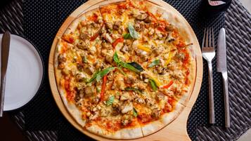 Pizza puulautalla, vieressä haarukka ja veitsi.