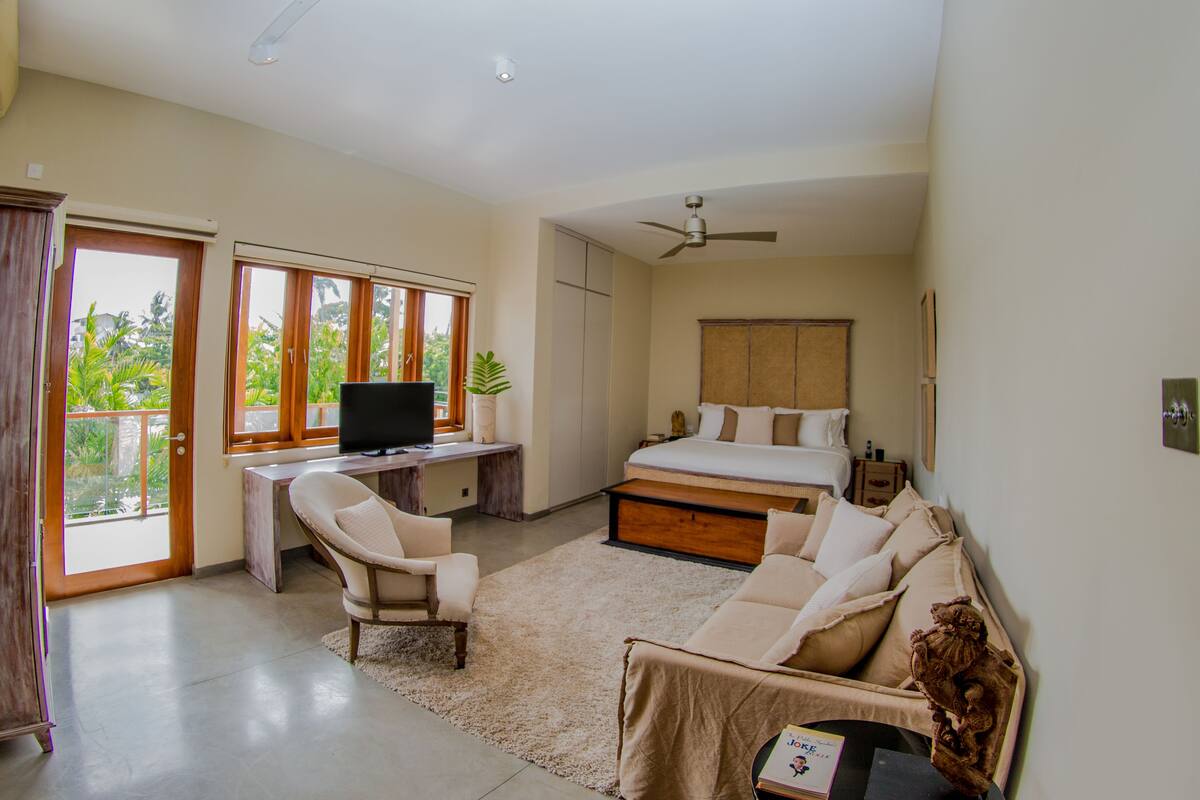 A bedroom with a bed, a desk, a chair, a sofa, and a television.