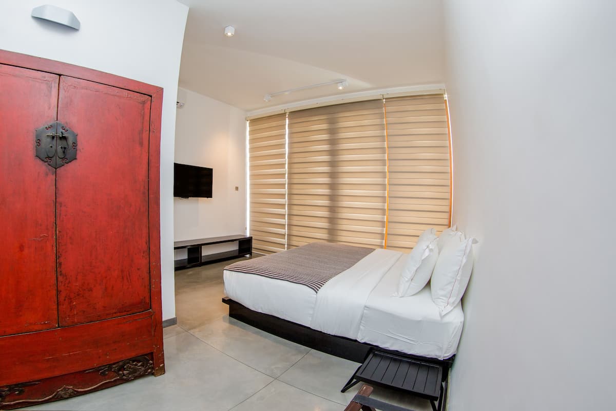 A bedroom with a bed, a television, and a wardrobe.