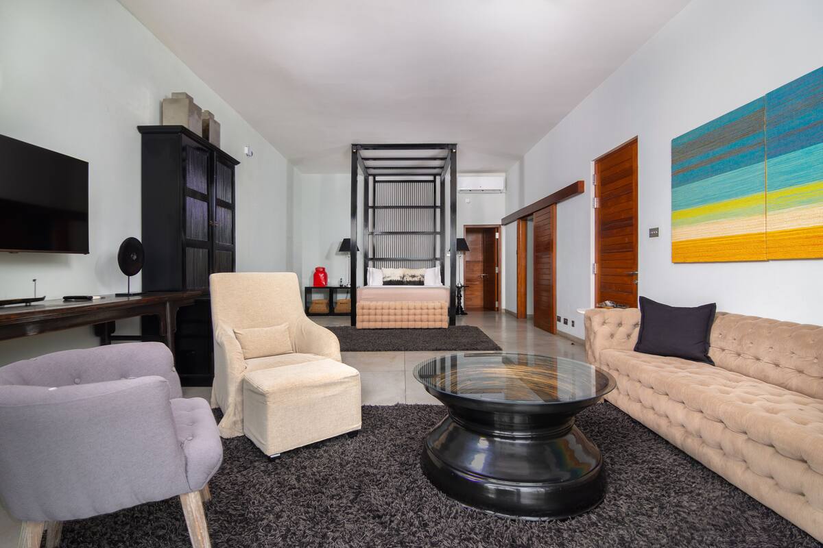 A modern living room with a sofa, armchair, and coffee table, a TV, and a bookshelf.