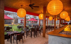 An outdoor dining area with wicker furniture, red umbrellas, and hanging spherical lanterns. - W15 Weligama (Weligama)