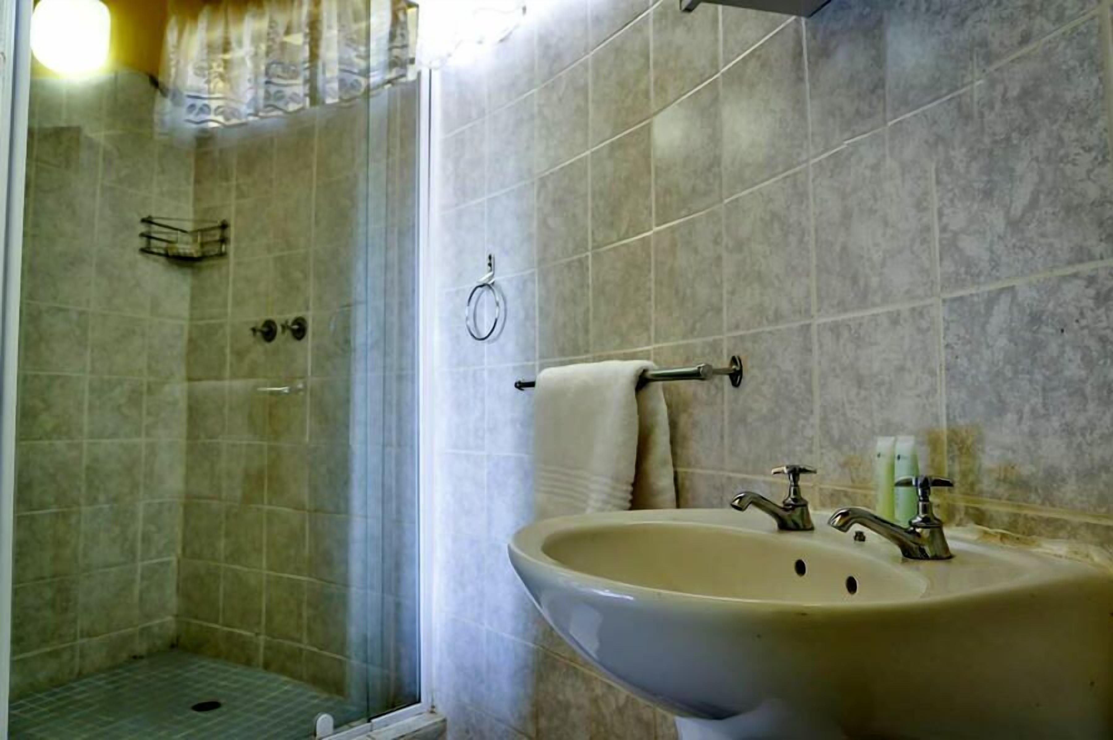 A bathroom with a shower, a sink, and a towel rack.