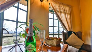 Una mesa con una botella de vino J.C. Penney, dos copas, una cesta de fruta y vistas al exterior a través de amplios ventanales.