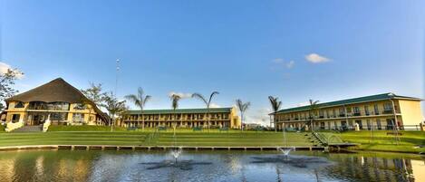 A hotel with a large pool, a tennis court, and a well-maintained lawn.