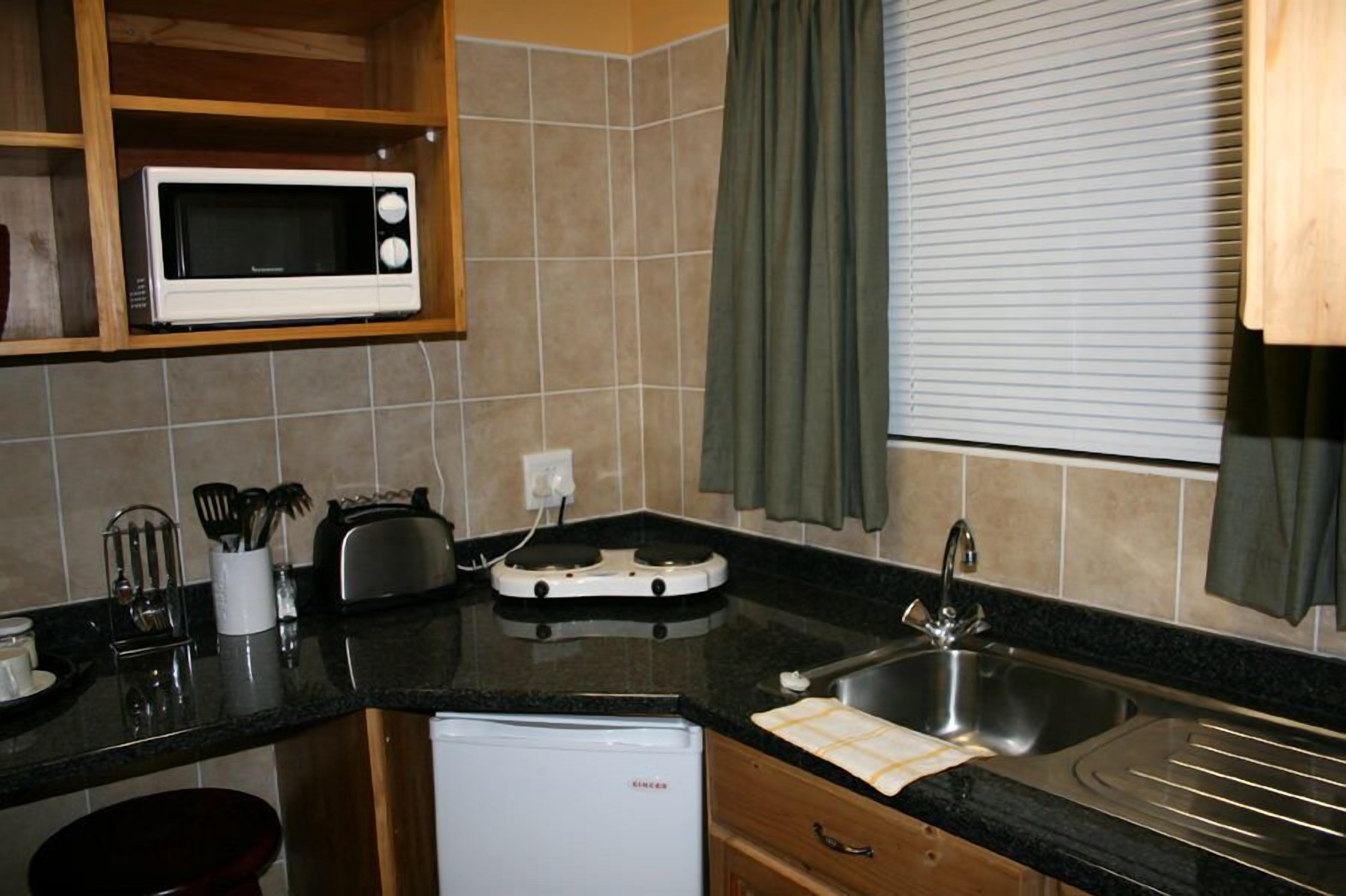 A compact kitchen with a microwave, toaster, and sink.