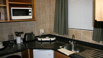A compact kitchen with a microwave, toaster, and sink.