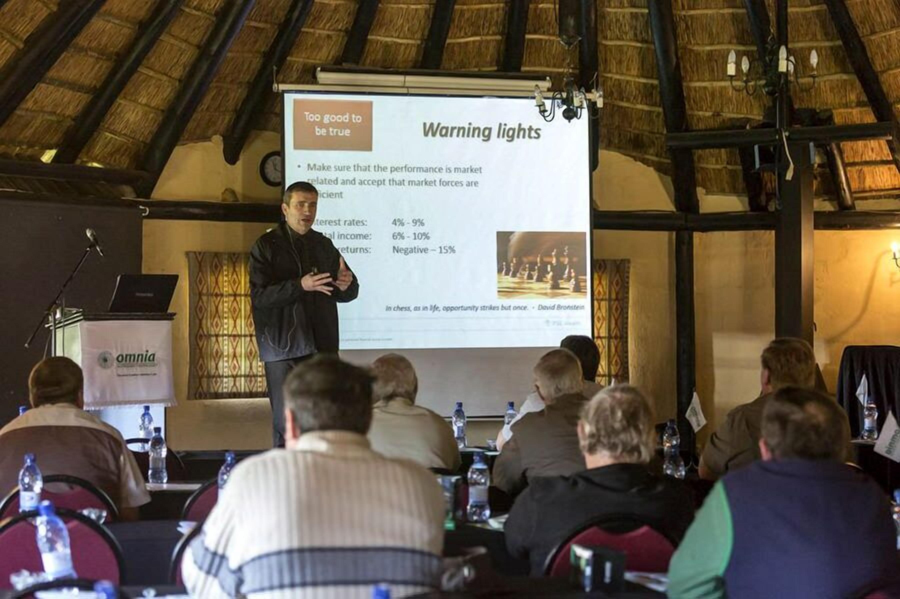 A conference room with a presentation screen displaying a slide titled "Warning lights" and a speaker addressing the audience.