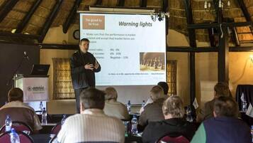 A conference room with a presentation screen displaying a slide titled "Warning lights" and a speaker addressing the audience.