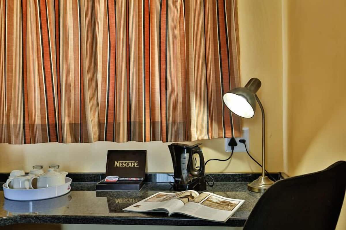A hotel room with a Nescafé coffee station, a coffee maker, a lamp, and a magazine on the counter.
