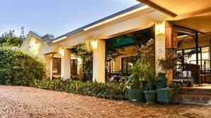 A hotel with a covered entrance, outdoor seating area, and a brick pathway leading to the entrance.