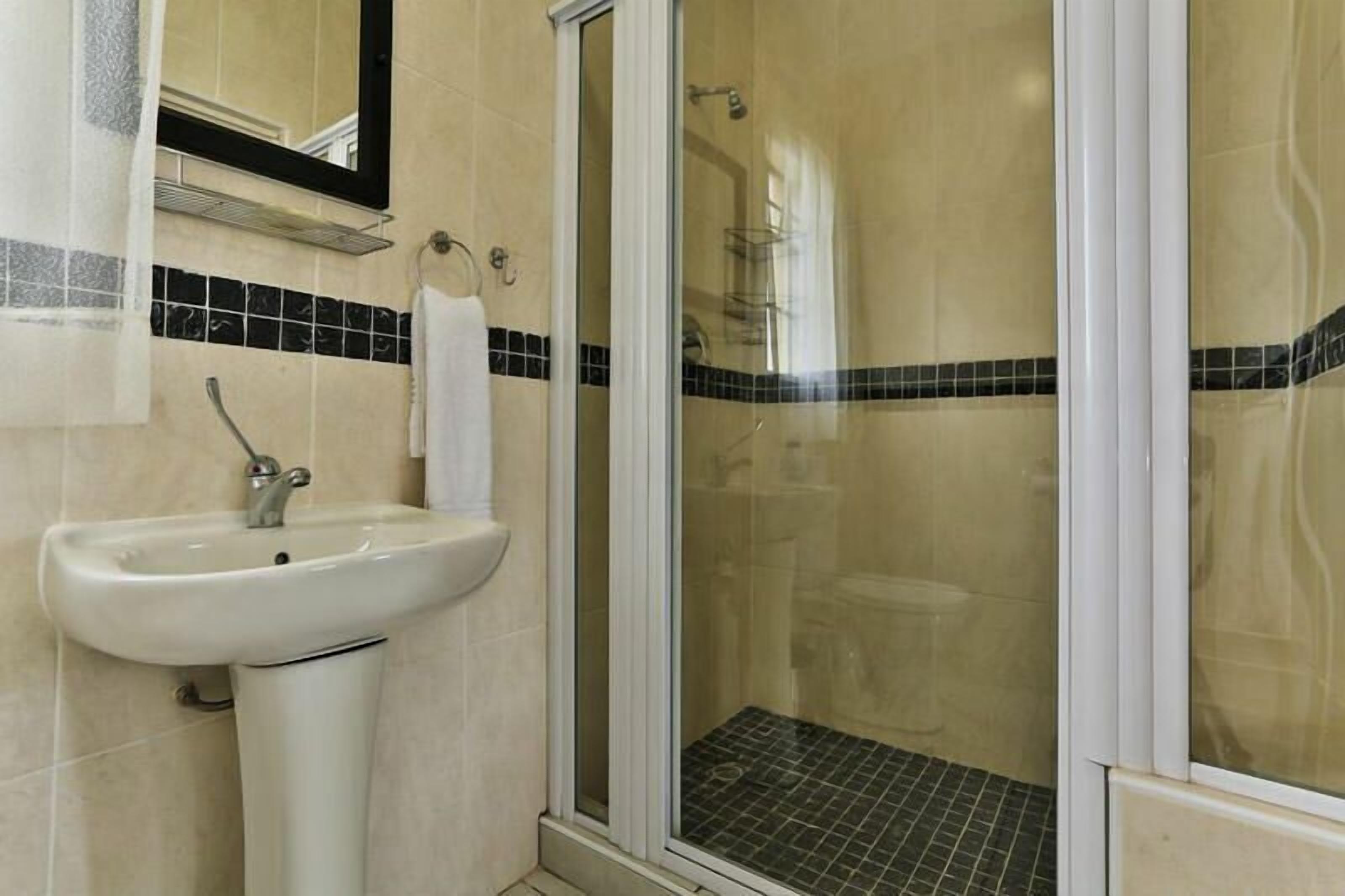 A bathroom with a sink, a mirror, and a shower enclosure.
