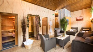 A spa area with wooden benches, wicker furniture, and a large plant. - Pension St. Leonhard (Bad Gastein)