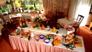 A dining area with a table set for a meal, surrounded by chairs and potted plants. - Pension St. Leonhard (Bad Gastein)