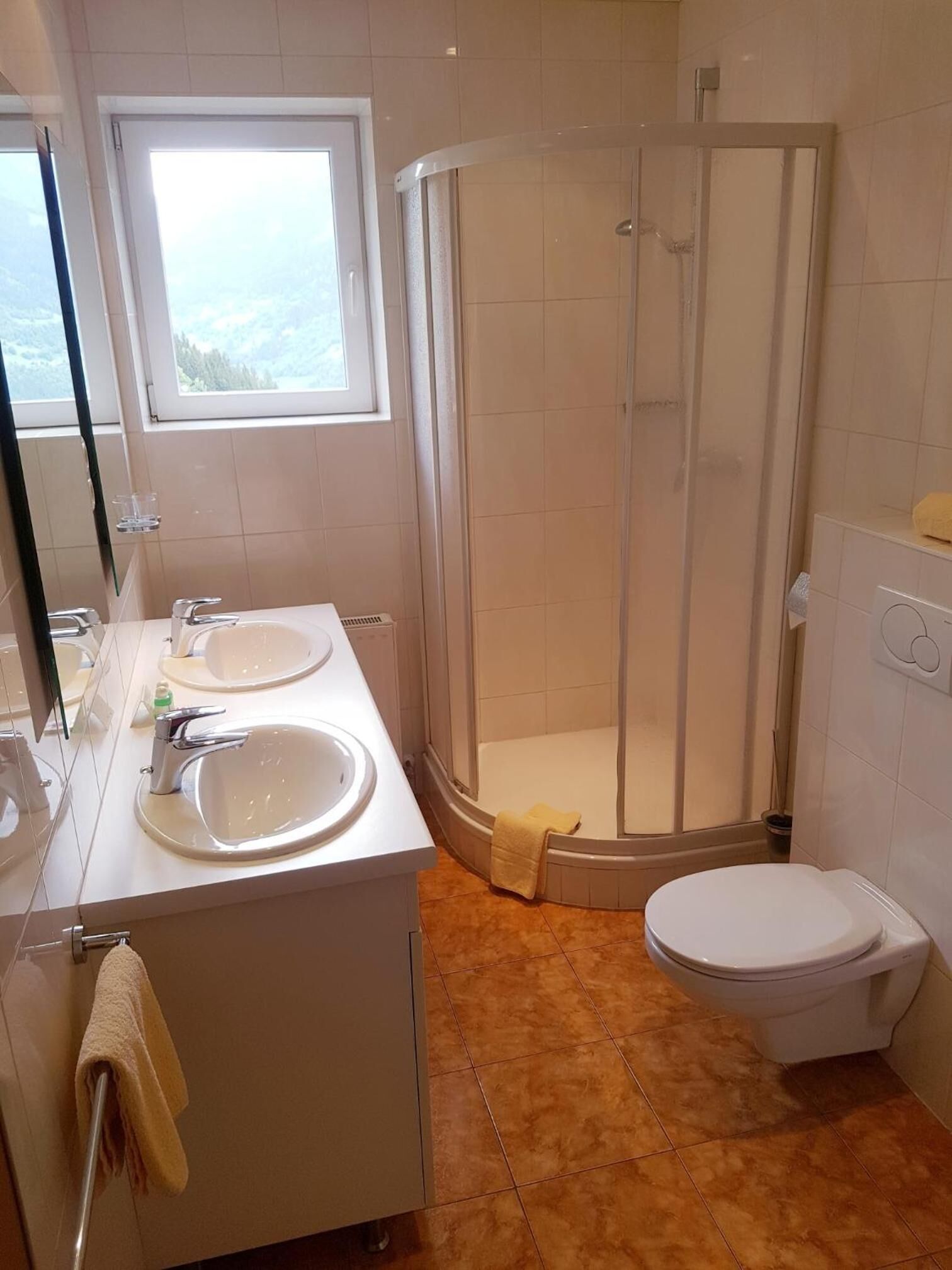 Un baño con dos lavabos, un inodoro y ducha con mampara de vidrio.