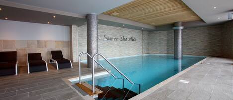 Una piscina techada, sillones reclinables de piscina