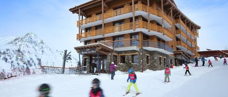 Un edificio a più piani con balconi e una pista da sci sullo sfondo.