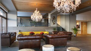 A spacious lobby with leather sofas, birchwood stools, and a chandelier. - Chalet des Neiges - LA SOURCE DES ARCS (Bourg-Saint-Maurice)
