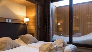 A hotel room with a bed, pillows, a bedside lamp, and a window with curtains. - Chalet des Neiges - LA SOURCE DES ARCS (Bourg-Saint-Maurice)