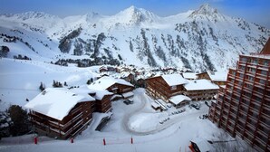 A snow-covered mountain resort with chalet-style buildings, a ski slope, and a clear blue sky. - Chalet des Neiges - LA SOURCE DES ARCS (Bourg-Saint-Maurice)