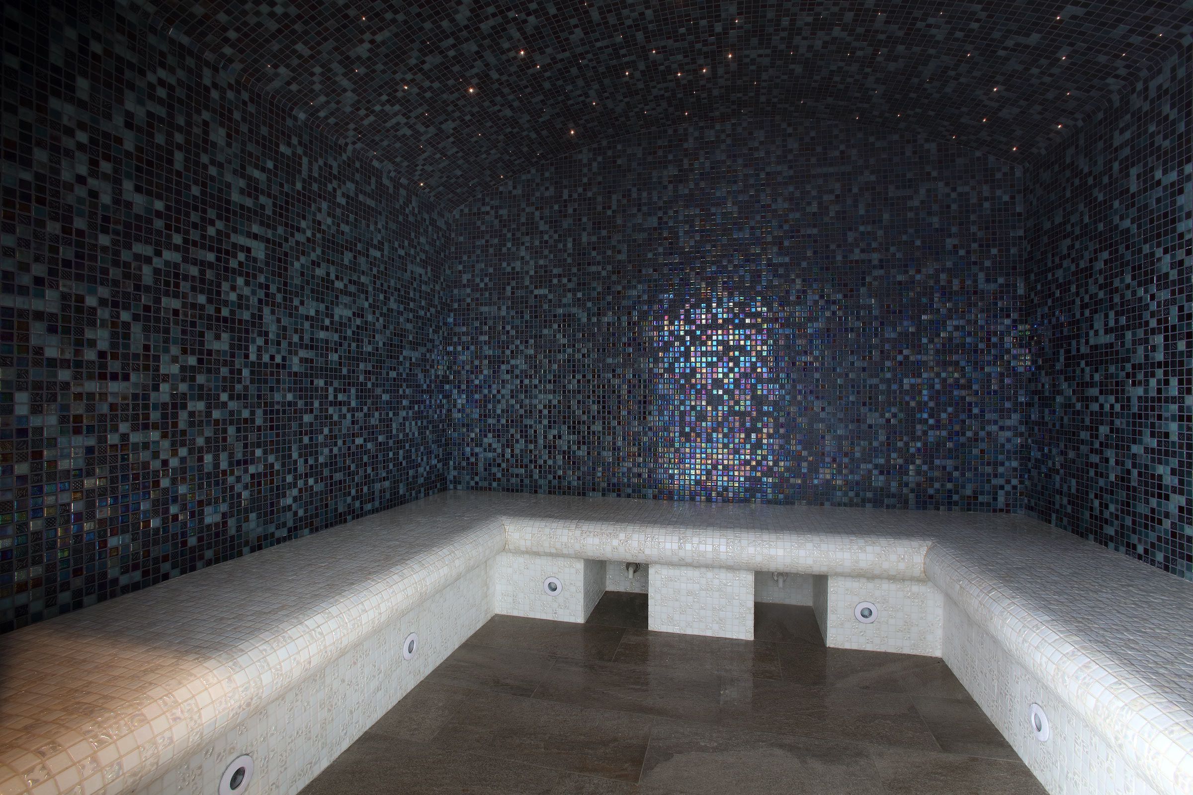 A tiled room with a bench and a small pool.