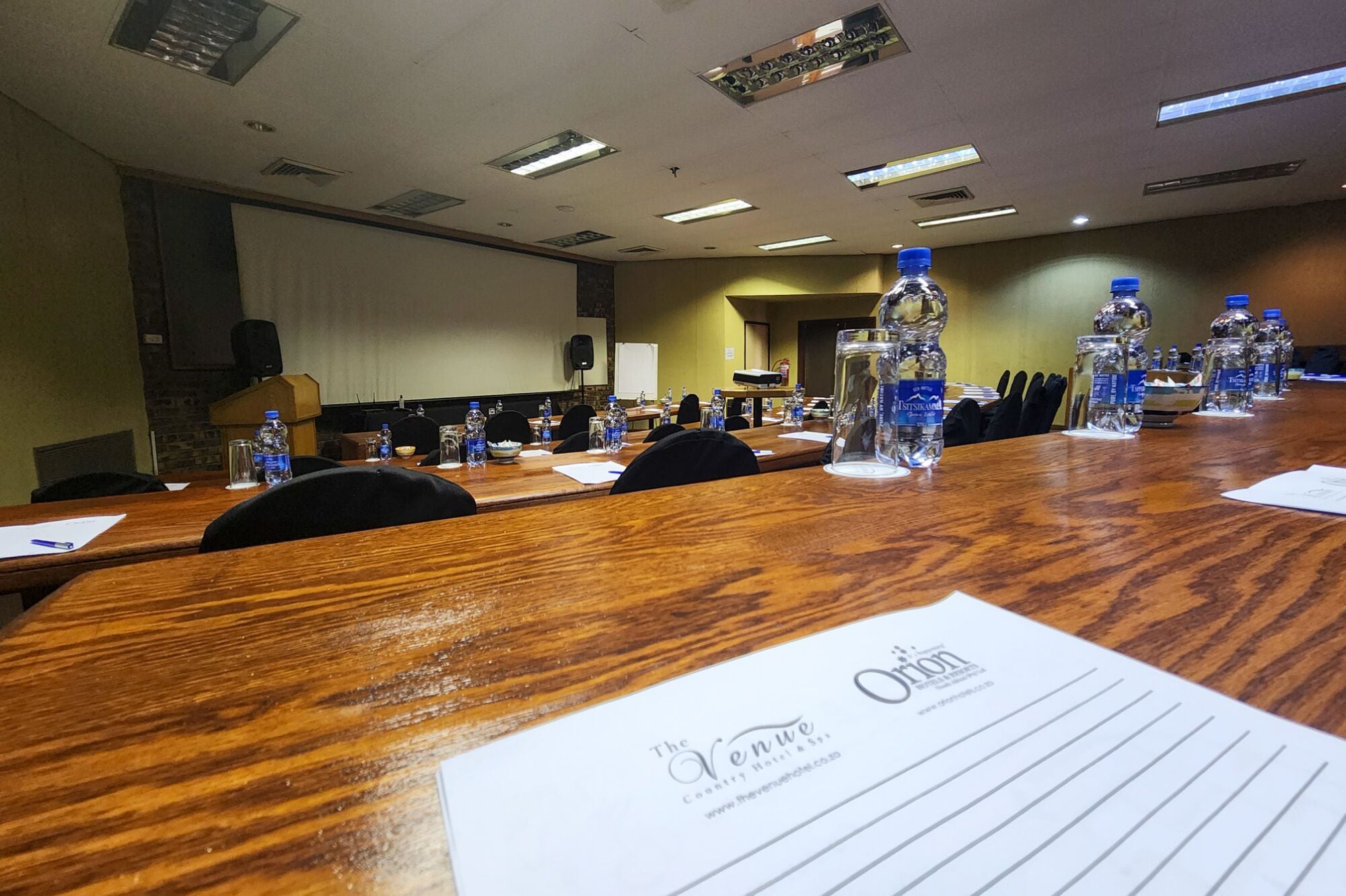 A conference room with wooden tables, water bottles, and a whiteboard.