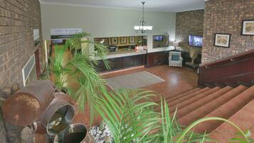 Um lobby com parede de tijolos, balcão de recepção, escada e lustre.