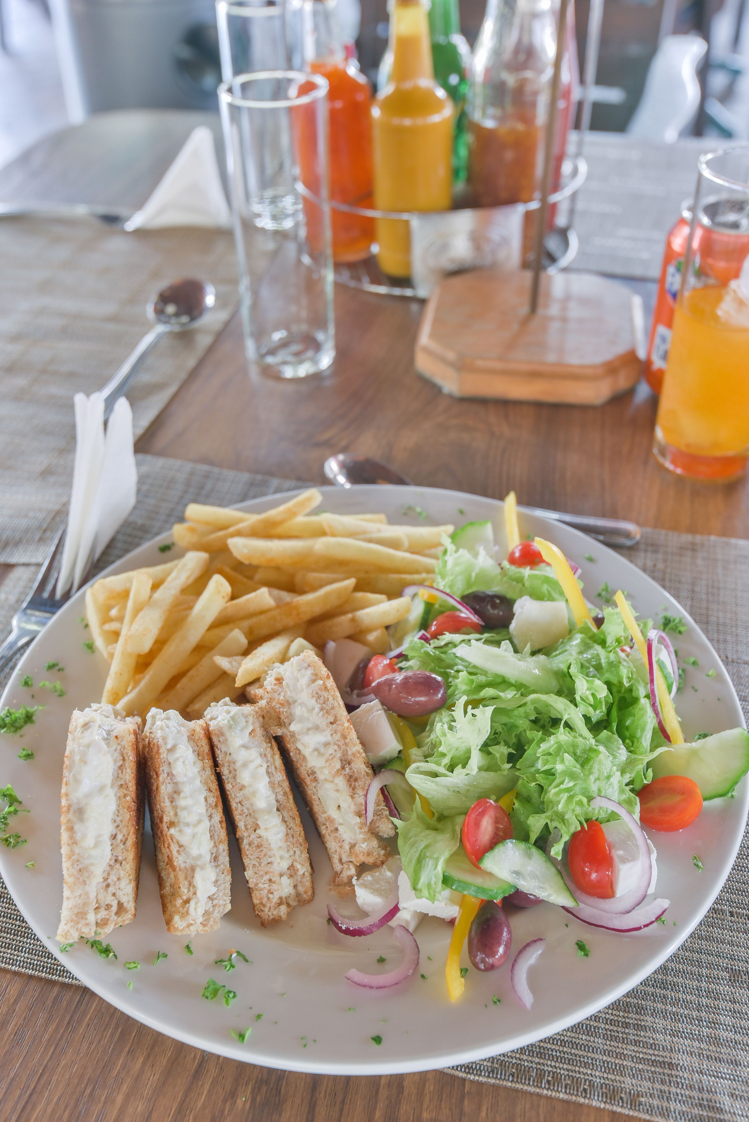 A plate with French fries, a sandwich, and a salad on a table.