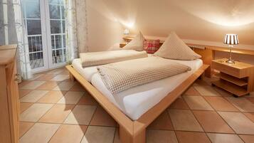 Un dormitorio con dos camas, una mesita de noche de madera, una lámpara y vistas a través de una puerta corredera.