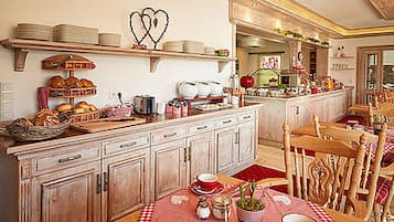 Una cocina con armarios de madera, una mesa de comedor con mantel a cuadros rojo y blanco, y diversos utensilios de cocina sobre las encimeras.