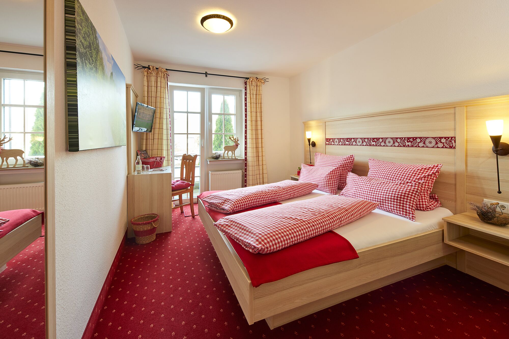 Een slaapkamer met een bed, een bureau, een stoel, een televisie en een raam met gordijnen.
