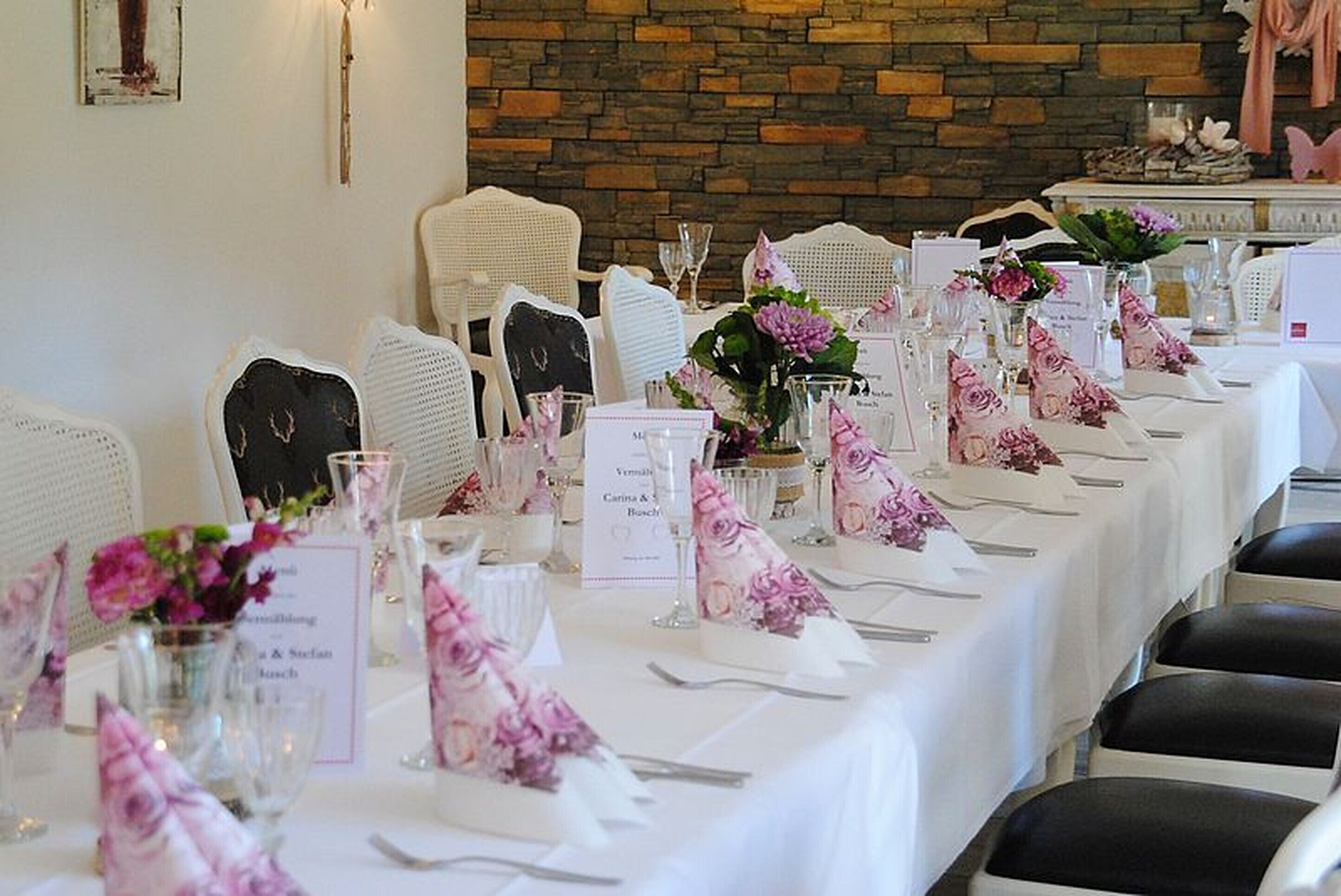 Una larga mesa dispuesta para un evento formal, con manteles blancos, centros de mesa florales y tarjetas con nombres.