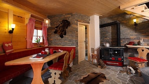A cozy cabin interior with a stone fireplace, wooden furniture, and a bench. - Hotel Dorfkammer (Olsberg)