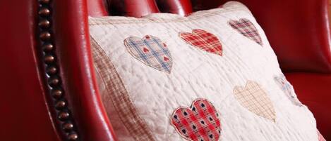 A red leather chair with a quilted pillow featuring heart patterns.