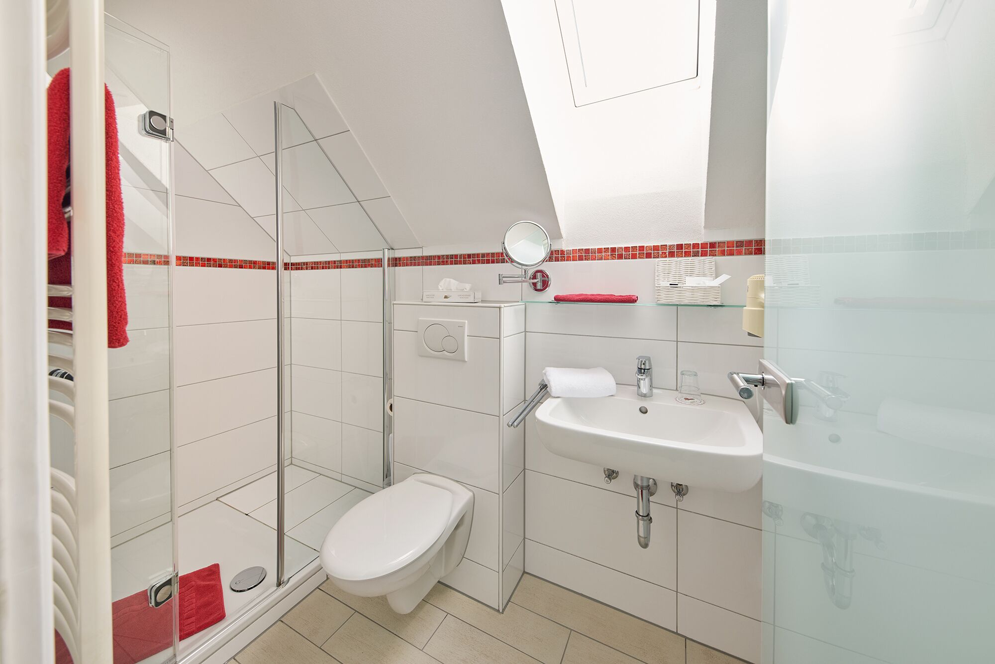 A modern bathroom with a glass shower enclosure, a white toilet, and a sink with a mirror above it.