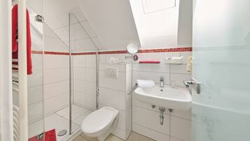 A modern bathroom with a glass shower enclosure, a white toilet, and a sink with a mirror above it.