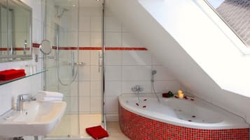 Ein modernes Badezimmer mit einer gläsernen Duschkabine, einem weißen Waschbecken und einer roten Badewanne im Whirlpool-Design.