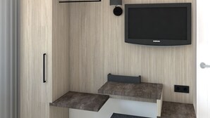 Quarto moderno com televisão integrada, mesa de cabeceira e unidade de armazenamento.