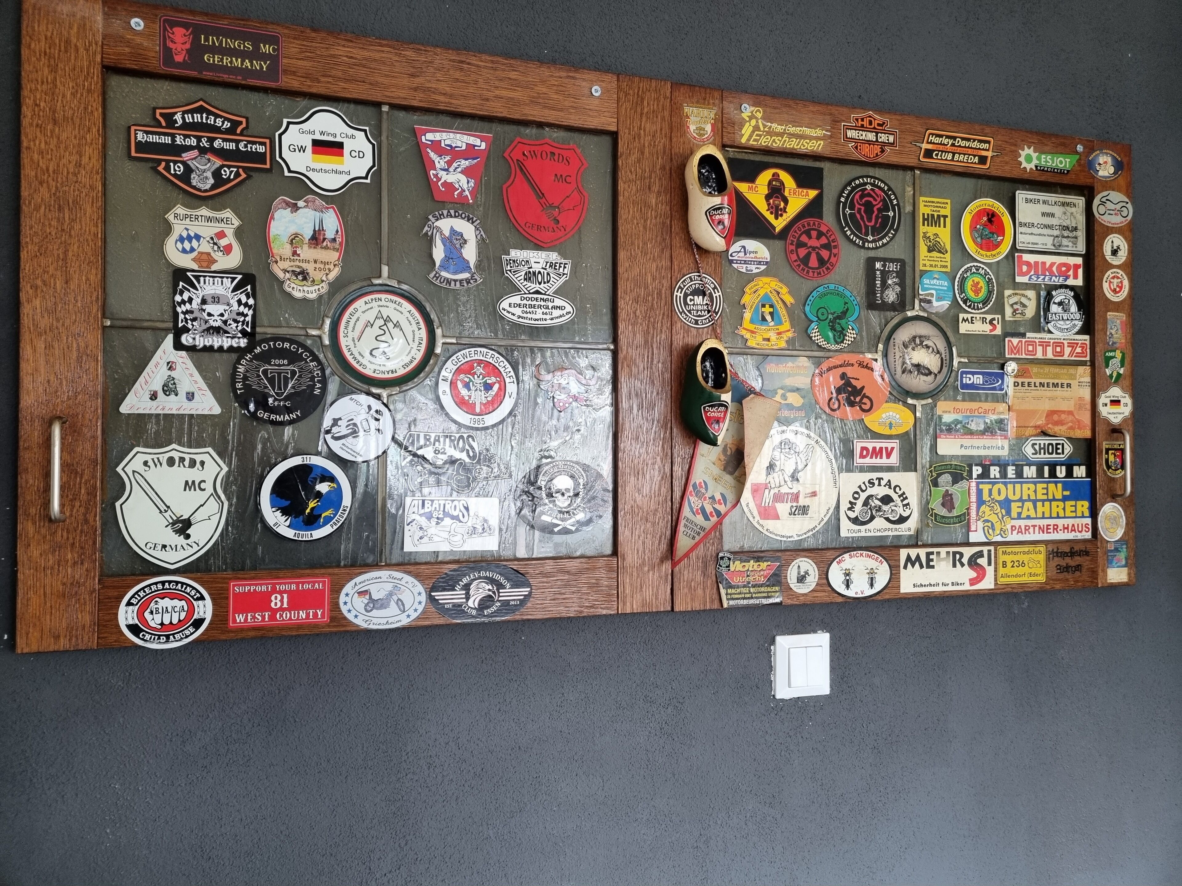 Een muur met een verzameling motorfiets- en racestickers, sommige met tekst en andere met logo's.