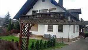 Uma casa de dois andares com varanda e cerca de madeira.