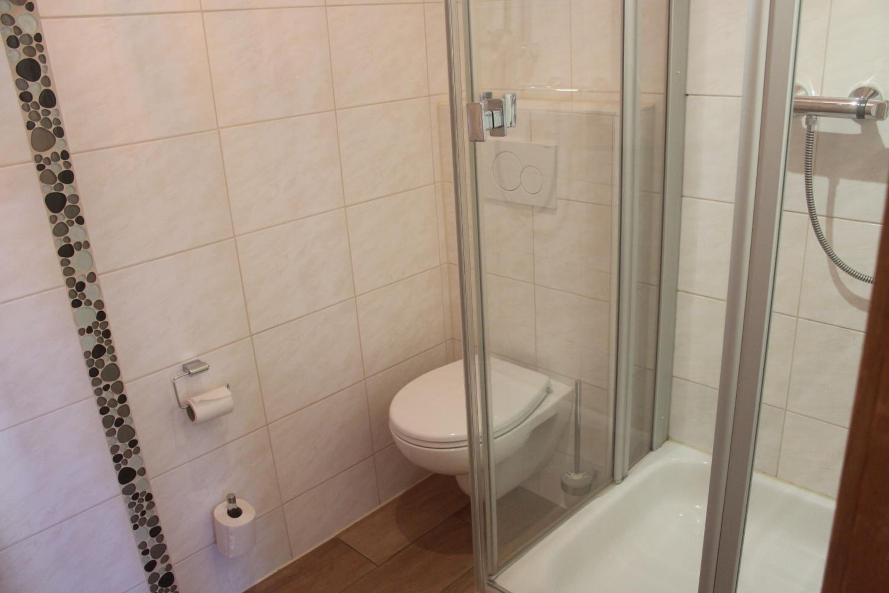 A bathroom with a glass-enclosed shower, a toilet, and a bathtub.