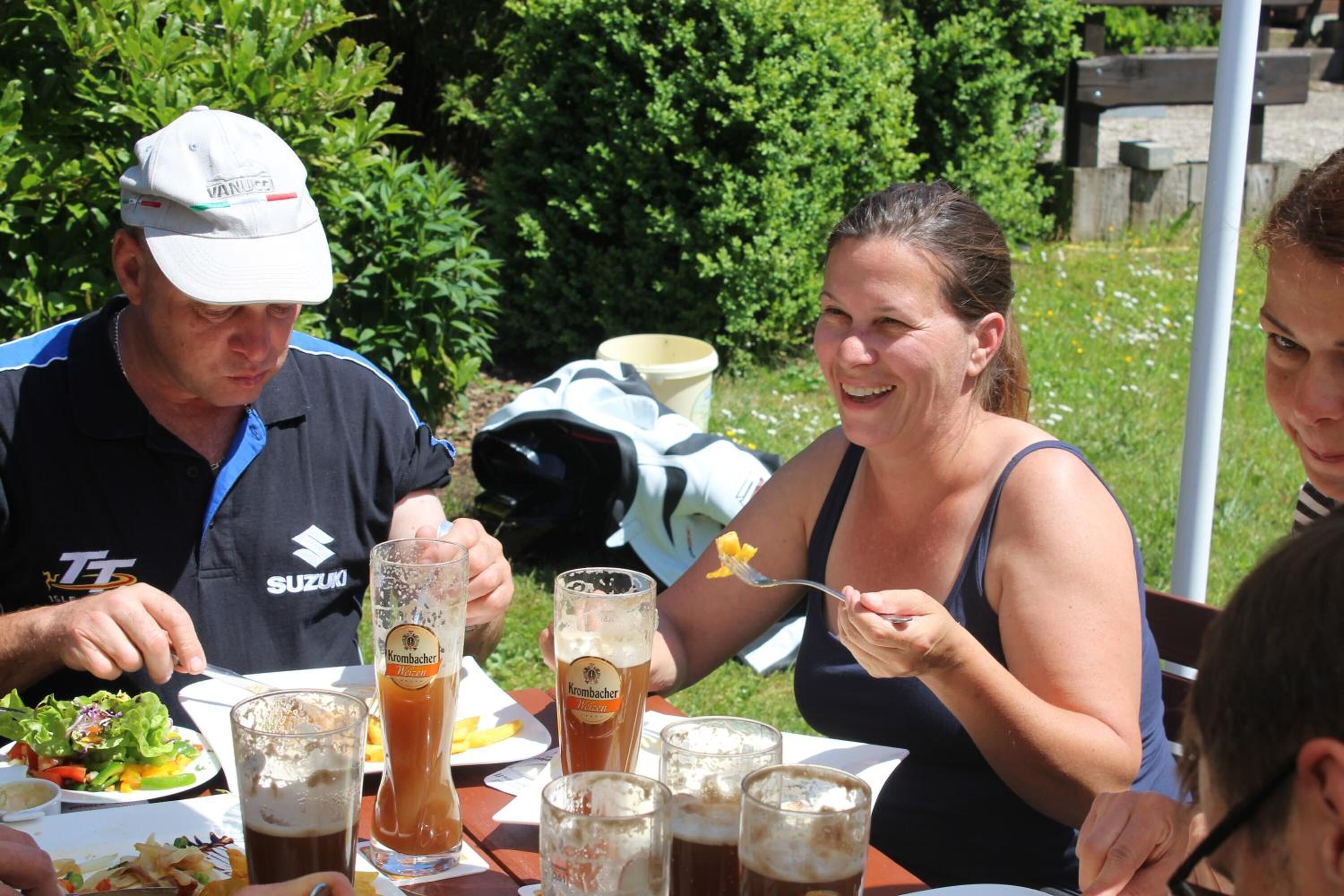 A group of people dining outdoors at a table with various dishes and drinks.