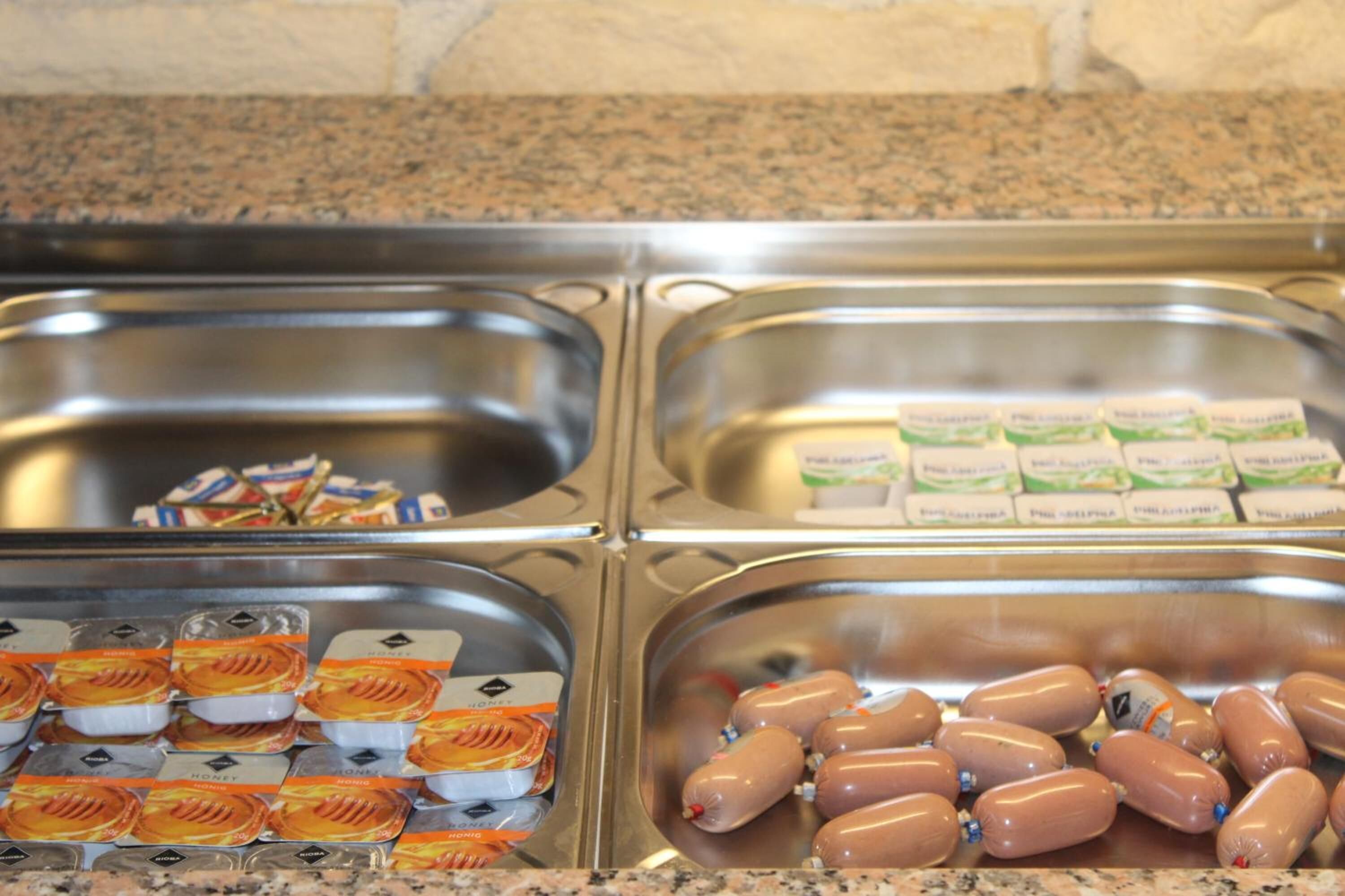 A buffet with three sections: one with packaged food, one with sausages, and one with milk cartons.
