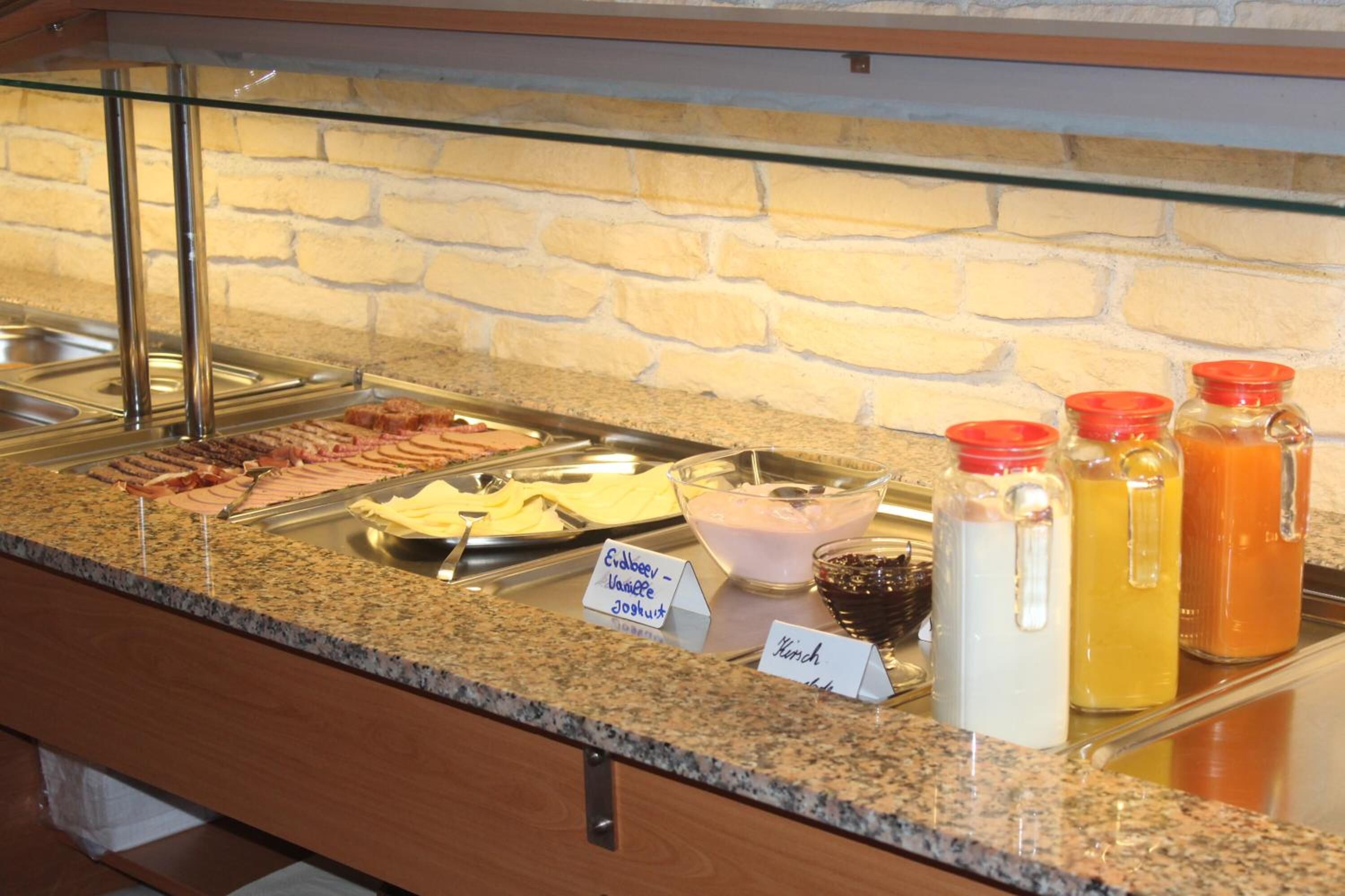 A buffet with various food items and condiments, including a sign for 'Edelbeer Vanillee' and 'Kirsche'.